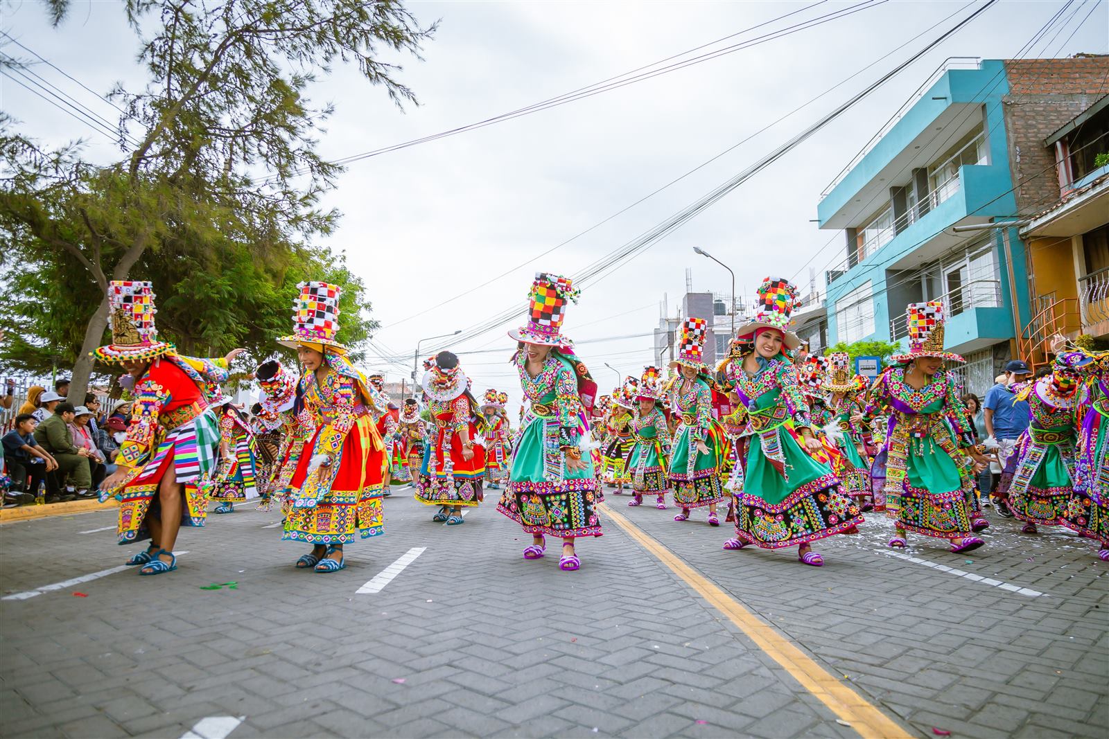 Grupo em trajes tradicionais coloridos durante desfile cultural de rua